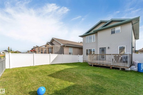 Expansive green lawn with a white privacy fence, multi-level vinyl siding exterior, and a wooden deck - 4510 164A Ave Nw, Edmonton, AB 