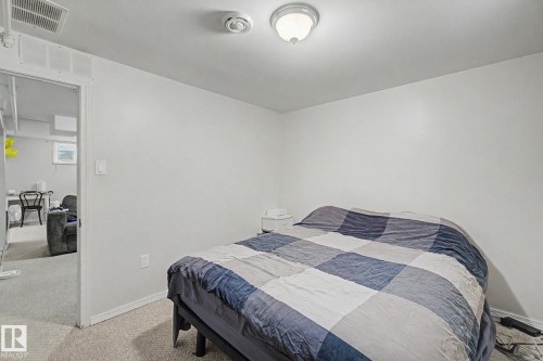 Neutral white walls with a ceiling-mounted light fixture and carpeted flooring - 8710 83 Avenue Nw, Edmonton, AB - Indoor Photo Showing Bedroom