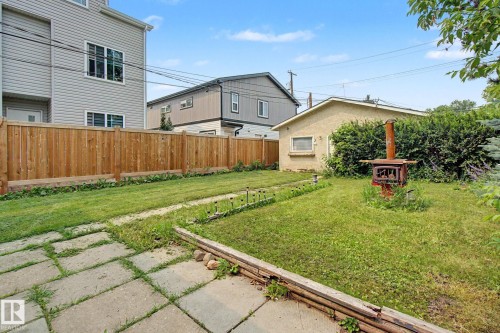 Expansive backyard featuring a large grass area, concrete paver patio, and full-height wood fencing - 8710 83 Avenue Nw, Edmonton, AB - Outdoor