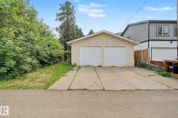 Detached two-car garage with white paneled doors and stucco exterior - 