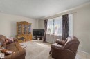 Carpeted living space with a large window, neutral wall paint, and a textured ceiling - 8710 83 Avenue Nw, Edmonton, AB  - Indoor Photo Showing Living Room 