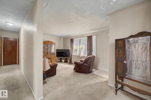 Carpeted living area with a large window and a ceiling-mounted light fixture - 8710 83 Avenue Nw, Edmonton, AB - Indoor