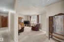 Carpeted living area with a large window and a ceiling-mounted light fixture - 8710 83 Avenue Nw, Edmonton, AB  - Indoor 
