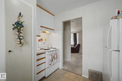 Compact kitchen featuring white cabinetry, white electric range, and a tile backsplash - 8710 83 Avenue Nw, Edmonton, AB - Indoor Photo Showing Kitchen