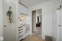 Compact kitchen featuring white cabinetry, white electric range, and a tile backsplash - 
