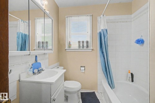 Bathroom featuring a white vanity with integrated sink, toilet, and bathtub with overhead shower - 8710 83 Avenue Nw, Edmonton, AB - Indoor Photo Showing Bathroom