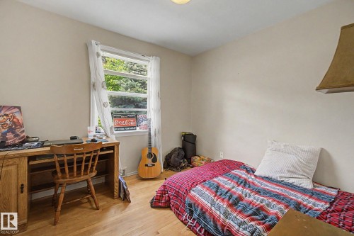 Room featuring wood-finish flooring, a window with exterior tree views, and light-toned wall finishes - 8710 83 Avenue Nw, Edmonton, AB - Indoor Photo Showing Bedroom