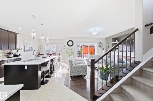 Kitchen island with solid surface countertop, dark wood-finish cabinetry, and contemporary pendant lighting - 144 52 Street Sw, Edmonton, AB 