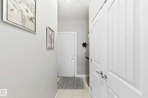 Hallway featuring light-toned tile flooring, recessed lighting, and white paneled doors - 144 52 Street Sw, Edmonton, AB 