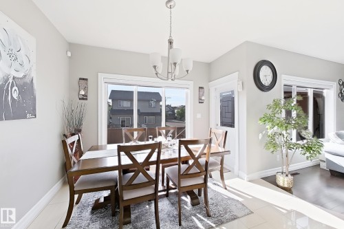 Dining area with light gray walls, white trim, and a contemporary chandelier - 144 52 Street Sw, Edmonton, AB 