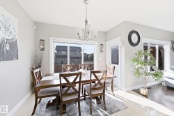 Dining area with light gray walls, white trim, and a contemporary chandelier - 