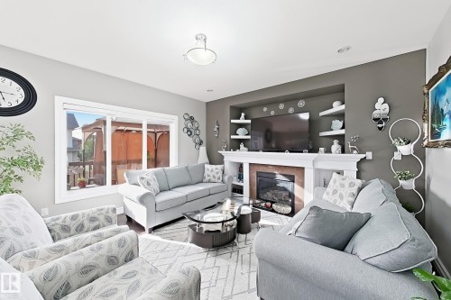 Built-in fireplace with a white mantel, recessed display shelves, sliding patio door, and recessed lighting - 144 52 Street Sw, Edmonton, AB 