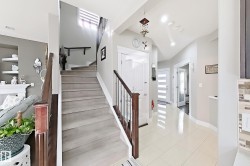 Grand entryway featuring a staircase with wood-finish treads and railing, ceramic tile flooring, and recessed lighting - 