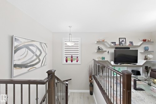 Wood-finish flooring, wrought iron stair railing, built-in shelving, window with horizontal blinds, and a suspended ceiling light fixture - 144 52 Street Sw, Edmonton, AB 