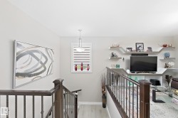 Wood-finish flooring, wrought iron stair railing, built-in shelving, window with horizontal blinds, and a suspended ceiling light fixture - 