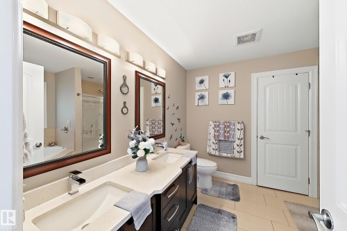 Double vanity with integrated sinks and chrome fixtures, framed mirrors, and overhead wall sconce lighting - 144 52 Street Sw, Edmonton, AB 