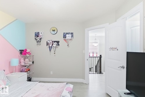 Painted accent wall, light wood-finish flooring, white interior doors, staircase with dark handrail and balusters, pendant lighting fixture - 144 52 Street Sw, Edmonton, AB 