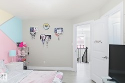 Painted accent wall, light wood-finish flooring, white interior doors, staircase with dark handrail and balusters, pendant lighting fixture - 