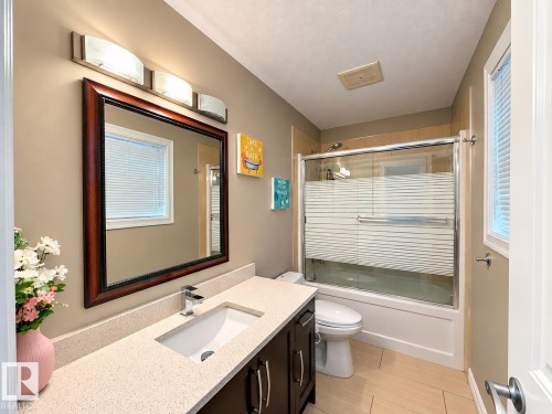 Vanity with an integrated sink, polished chrome faucet, and stone-finish countertop - 144 52 Street Sw, Edmonton, AB 