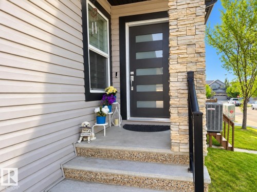 Modern entry door with horizontal frosted glass inserts, complemented by a stone veneer facade - 144 52 Street Sw, Edmonton, AB 