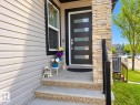 Modern entry door with horizontal frosted glass inserts, complemented by a stone veneer facade - 144 52 Street Sw, Edmonton, AB 