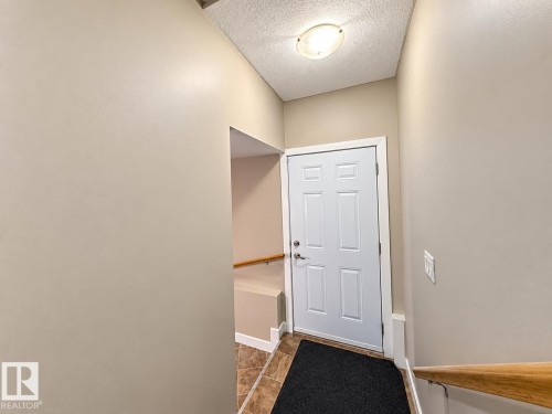 Six-panel entry door, neutral wall finishes, tile flooring, and a flush mount ceiling light fixture - 144 52 Street Sw, Edmonton, AB 