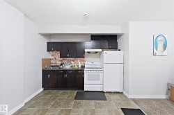 Kitchen featuring dark wood-finish cabinetry, white appliances, and a wood-look tile backsplash - 