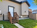Manicured lawn with a concrete walkway and wooden steps leading to an exterior door - 144 52 Street Sw, Edmonton, AB 