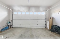 Attached garage with a white panel door and upper window lights, featuring a concrete floor and painted walls - 