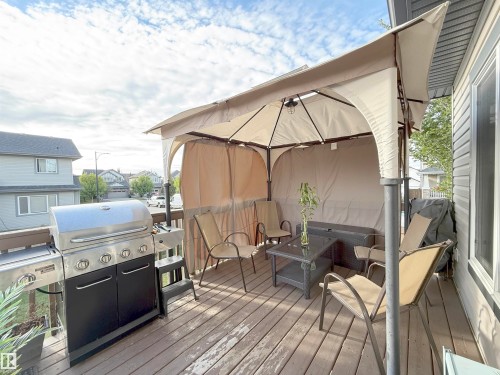 Spacious wood-finish deck with a built-in privacy wall, a covered gazebo structure, and a stainless steel grill - 144 52 Street Sw, Edmonton, AB 