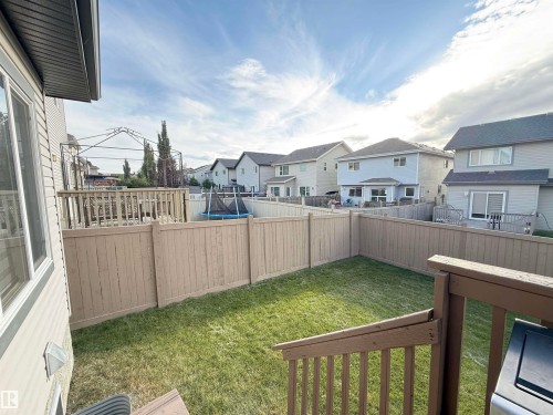 Expansive backyard featuring a manicured lawn, full perimeter fencing, and a multi-level wood deck - 144 52 Street Sw, Edmonton, AB 