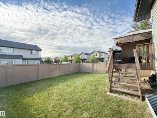 Expansive lawn with a full privacy fence, wood deck, and wood-finish railing - 144 52 Street Sw, Edmonton, AB 