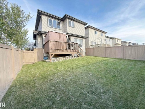 Spacious backyard with a large wood-finish deck, privacy fencing, and expansive green space - 144 52 Street Sw, Edmonton, AB 