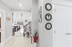 White interior doors, tile flooring, staircase with wood-finish handrail, recessed lighting, and wall paneling - 