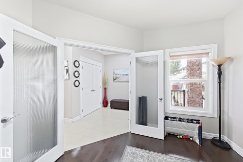 French doors with textured glass panels, wood-finish flooring, a double-paned window, and light-colored wall paint - 144 52 Street Sw, Edmonton, AB 