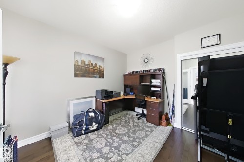 Hardwood-finish flooring, light neutral wall paint, and a built-in corner desk unit with shelving - 144 52 Street Sw, Edmonton, AB 