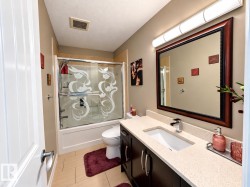 Recessed lighting, wood-finish vanity with a rectangular undermount sink, stone-finish countertop, and a framed mirror - 