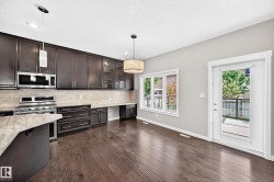 Dark wood-finish flooring, rich cabinetry, light-toned countertops, stainless steel appliances, and a glass-paneled exterior door - 