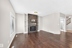 Stacked stone fireplace with an integrated firebox, flanked by built-in shelving and dark wood-finish flooring - 