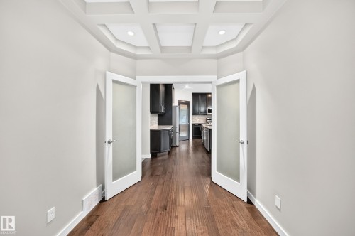 Coffered ceiling with recessed lighting, wood-finish flooring, and double doors with frosted glass panels - 3329 West Court Nw, Edmonton, AB 