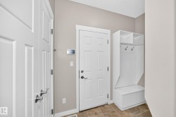 Entry area featuring tile flooring, white paneled doors, and a built-in storage bench with shelving and coat hooks - 