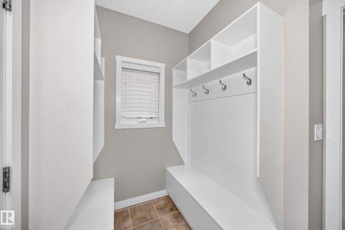 Built-in shelving unit with coat hooks and bench seating, complete with a window featuring blinds and tile flooring - 3329 West Court Nw, Edmonton, AB 