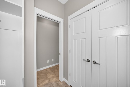 White paneled doors with brushed nickel hardware, tiled flooring, and neutral wall tones - 3329 West Court Nw, Edmonton, AB 