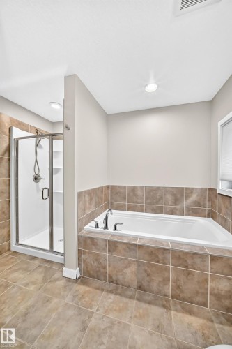 Tiled flooring, built-in soaking tub with deck-mounted fixtures, and a glass-enclosed shower with tiled surround - 3329 West Court Nw, Edmonton, AB 
