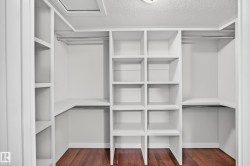 Custom built-in closet system featuring multiple shelves, hanging rods, and wood-finish flooring - 
