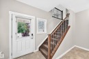Entryway featuring a paneled door with a glass insert, an adjacent window with blinds, a carpeted staircase with wood handrails and metal balusters, and tile flooring - 3329 West Court Nw, Edmonton, AB 