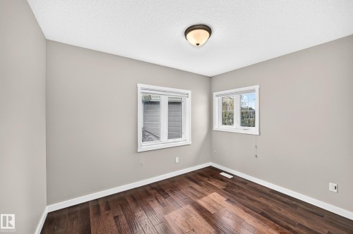 Wood-finish flooring with white trim, neutral wall paint, and two windows - 3329 West Court Nw, Edmonton, AB 
