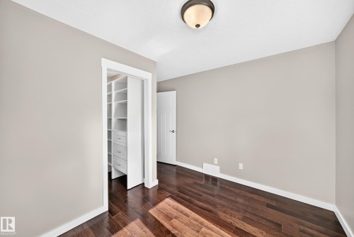 Wood-finish flooring, neutral wall tones, white trim, recessed ceiling light, and a built-in closet organization system - 3329 West Court Nw, Edmonton, AB 