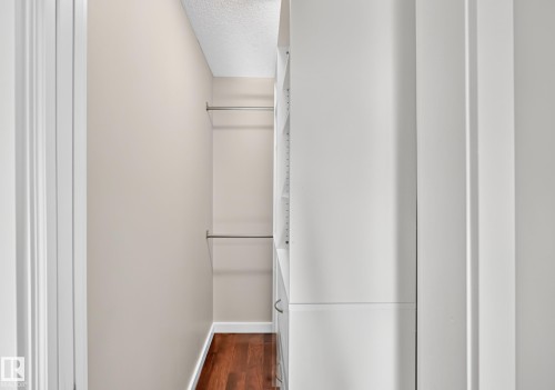 Walk-in closet with dual hanging rods, built-in shelving, wood-finish flooring, and neutral wall tones - 3329 West Court Nw, Edmonton, AB 