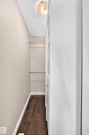 Built-in closet system with multiple drawers and shelving, wood-finish flooring, two clothing rods, and recessed lighting - 
